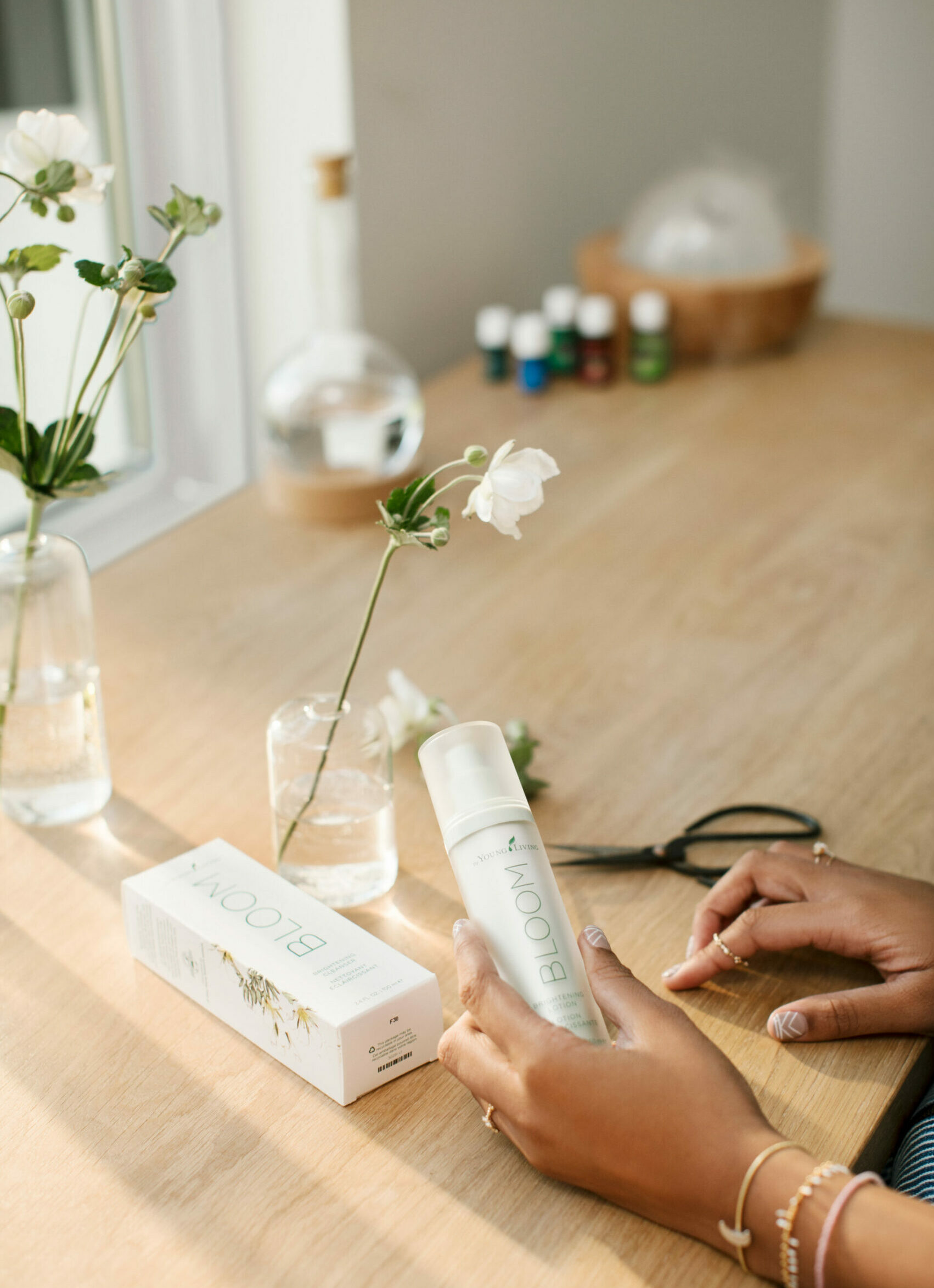 Woman holding BLOOM Brightening Lotion next to freshly cut flowers - Young Living Lavender Life Blog 