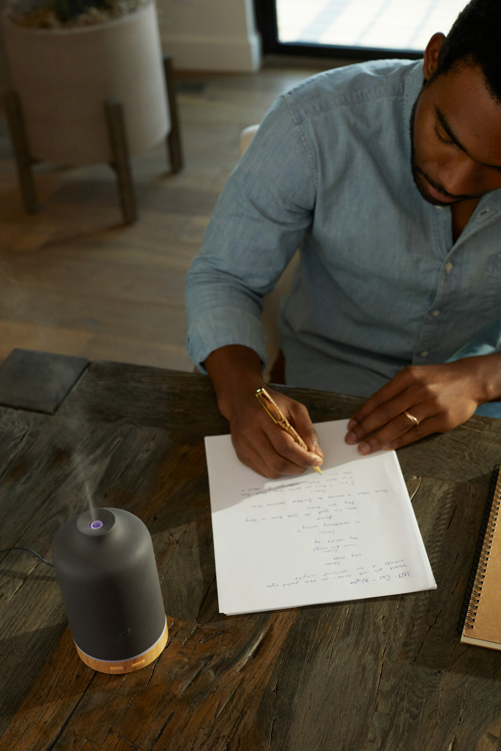 Man writing goals with Young Living ember diffuser