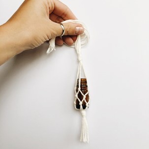 a hand holding a diy macramé diffuser